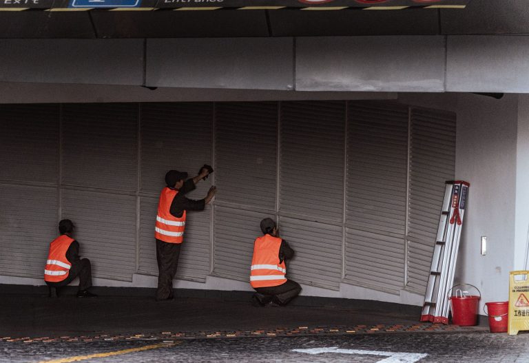 Three workers in safety vests install security shutters at an indoor entrance. — How to Set Up and Maintain Security Metal De